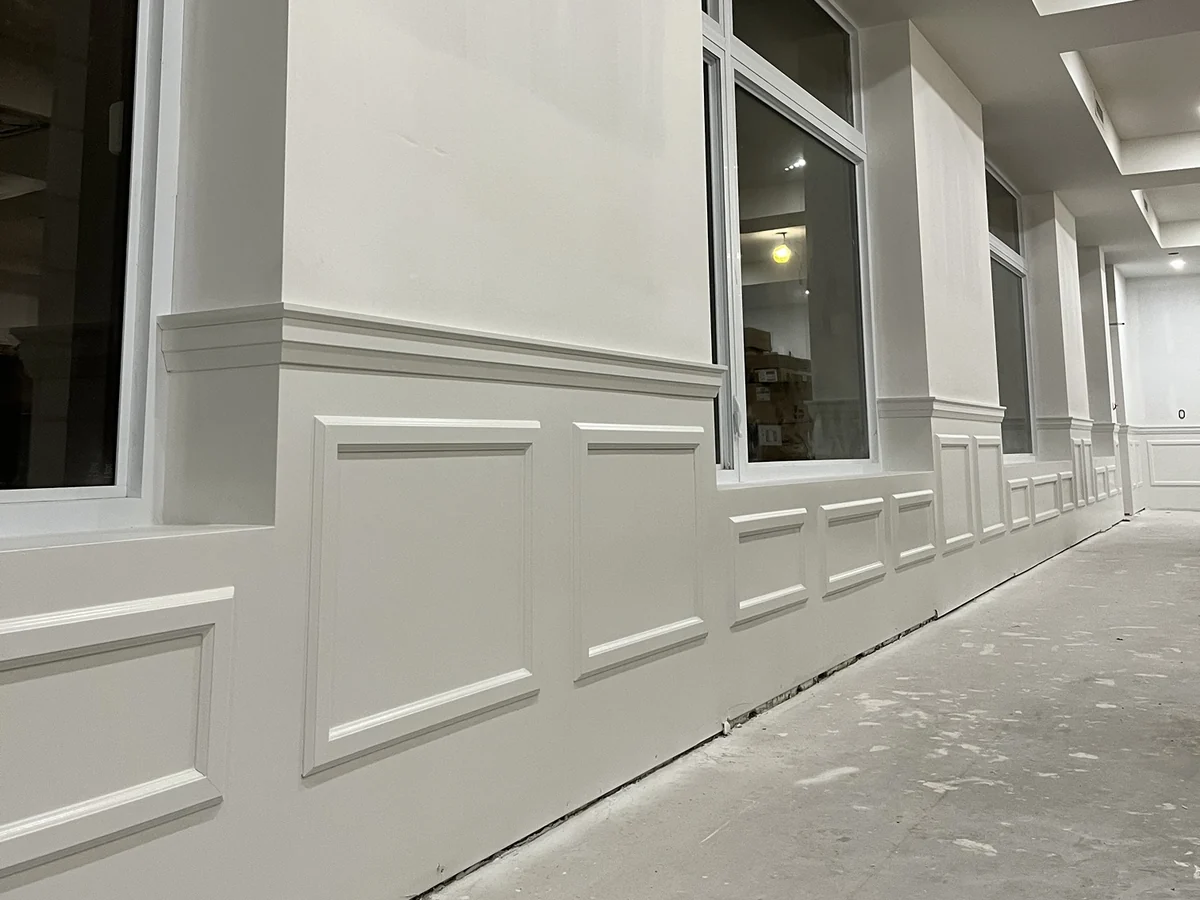 Raised-panel wainscoting and chair rail running along a corridor of windows
